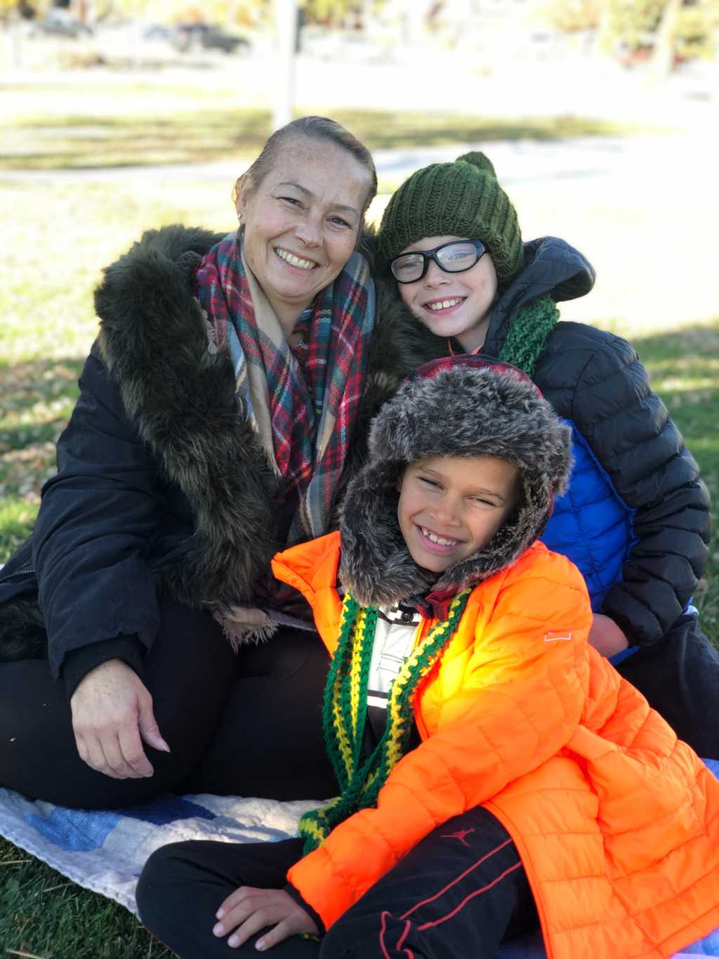 A mom and two smiling children in winter coats